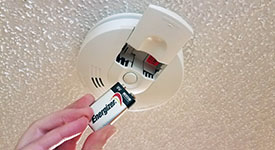 A battery being inserted into a smoke/CO alarm
