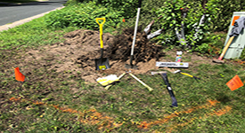 Digging tools, orange flags and markings on the ground.