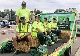 A group of volunteers with a local Community Emergency Response Team rides on a parade float