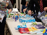 Basic necessities like personal hygiene products on a table as volunteers pack Care on the Go bags
