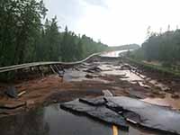 A washed out road with broken pieces of tar after flooding