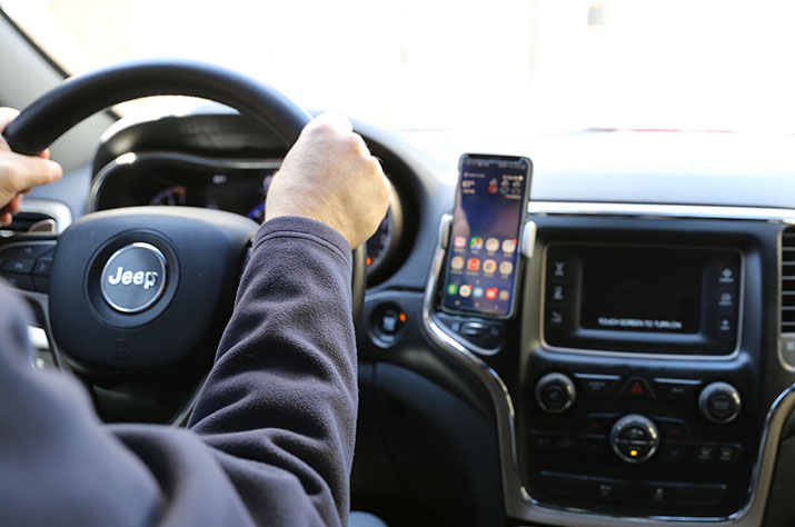 Hands on a steering wheel and a phone in a dash mount