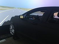 A driving simulator with a car appearing to drive along a road