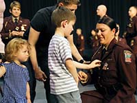 A Minnesota State Patrol Academy graduate’s young son pins on her badge at graduation