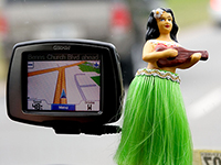 Photo of a GPS unit and hula doll in a car.