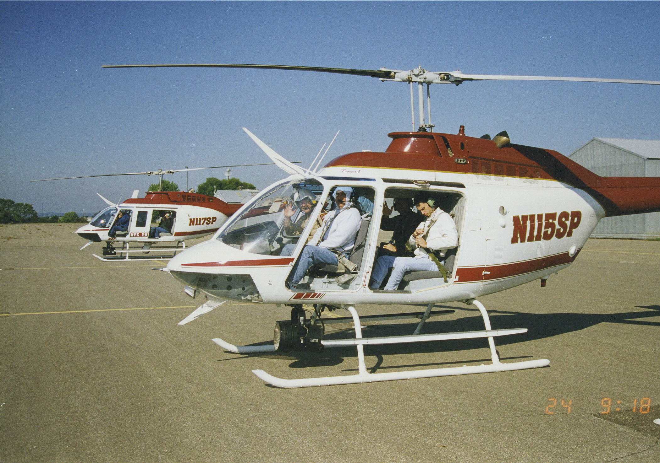 An early state patrol helicopter on the ground at an airport with four people inside