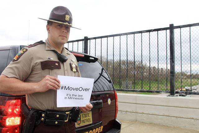 State Trooper holding a sign that says move over its the law in Minnesota