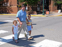 A man and two children using a crosswalk to cross a street