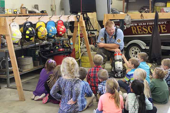 A firefighter talks with a group of children at a fire station