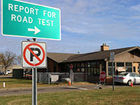 A sign that says report for road tests with a DVS exam station in the background