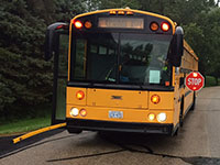 Photo of a school bus with lights flashing and stop arm extended.