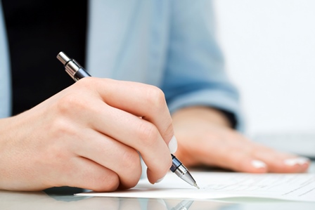 person signing a document in pen