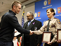Brandon Rausch (left) shakes Trooper Deanna Wayne’s hand while receiving a Meritorious Citizenship Award.